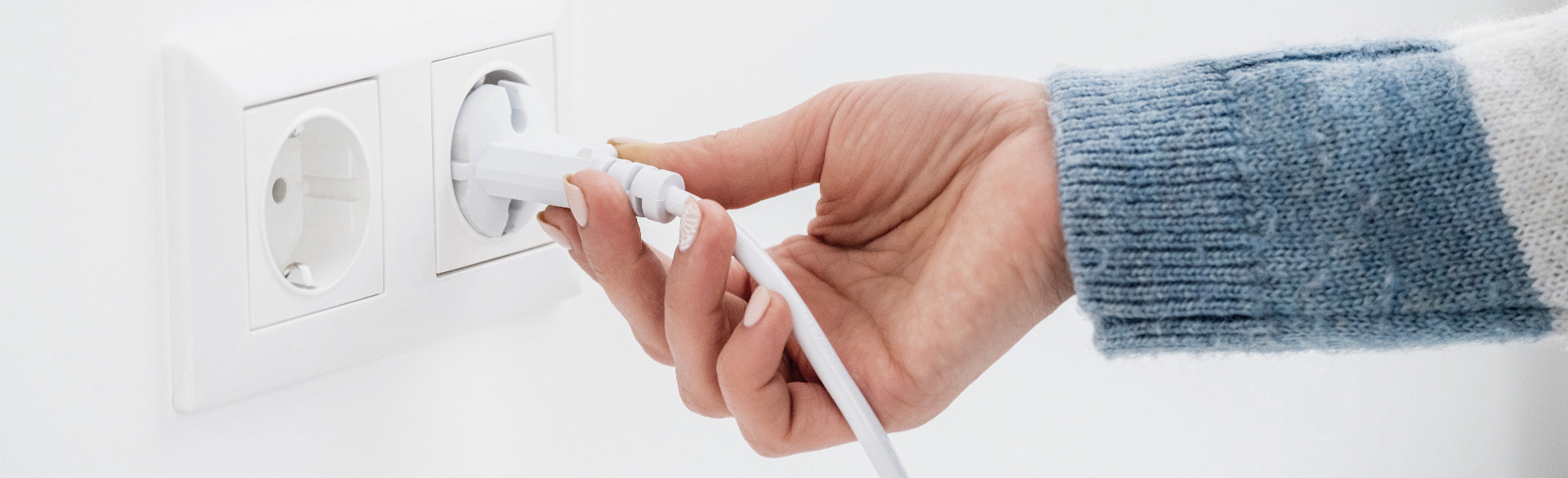 Hand, die einen Stecker in die Steckdose steckt
