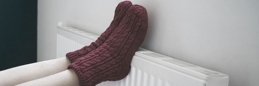 Heizkörper mit angelehnten Füßrn in roten Socken